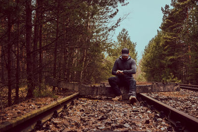 Man sitting on railroad track against trees