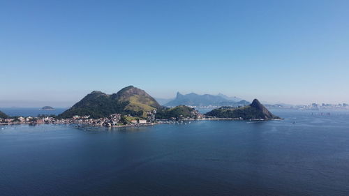 Scenic view of sea and mountains against clear blue sky