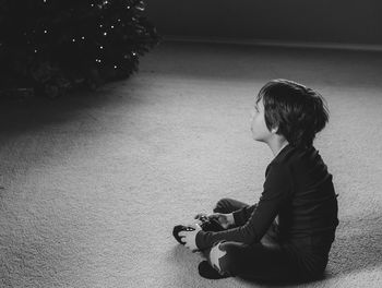 Side view of boy holding game controller while sitting at home