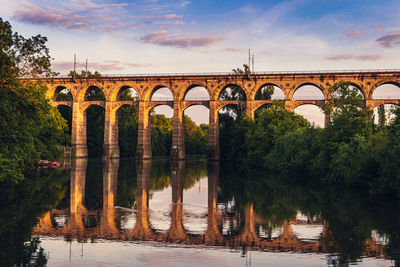 Arch bridge over river against sky