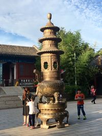 People standing outside temple against sky