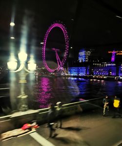 Illuminated ferris wheel in city at night