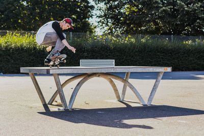 Side view of man cycling on bench in park