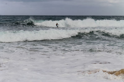 Man surfing in sea against sky