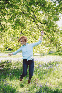Happy young woman jumping over grassy field