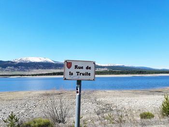 Information sign by mountains against clear blue sky