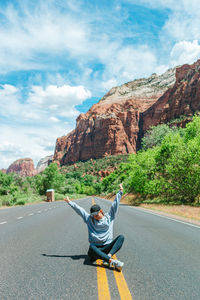 Rear view of man walking on road against mountain
