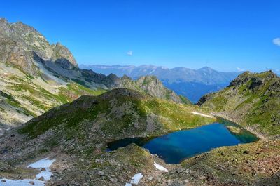 Scenic view of lake and mountains against clear blue sky