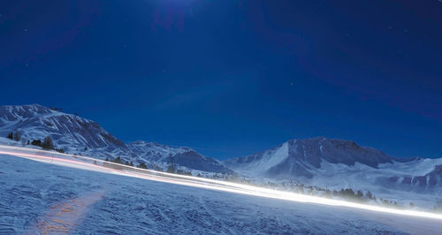 Scenic view of snowcapped mountains against blue sky at night