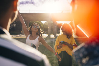 Playful woman having fun with friends during music festival on sunny day