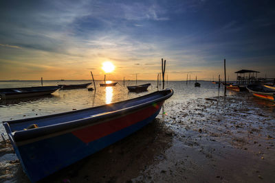 Boats moored on sea against sky during sunset