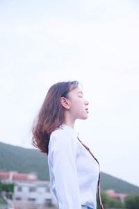 Young woman looking away against sky