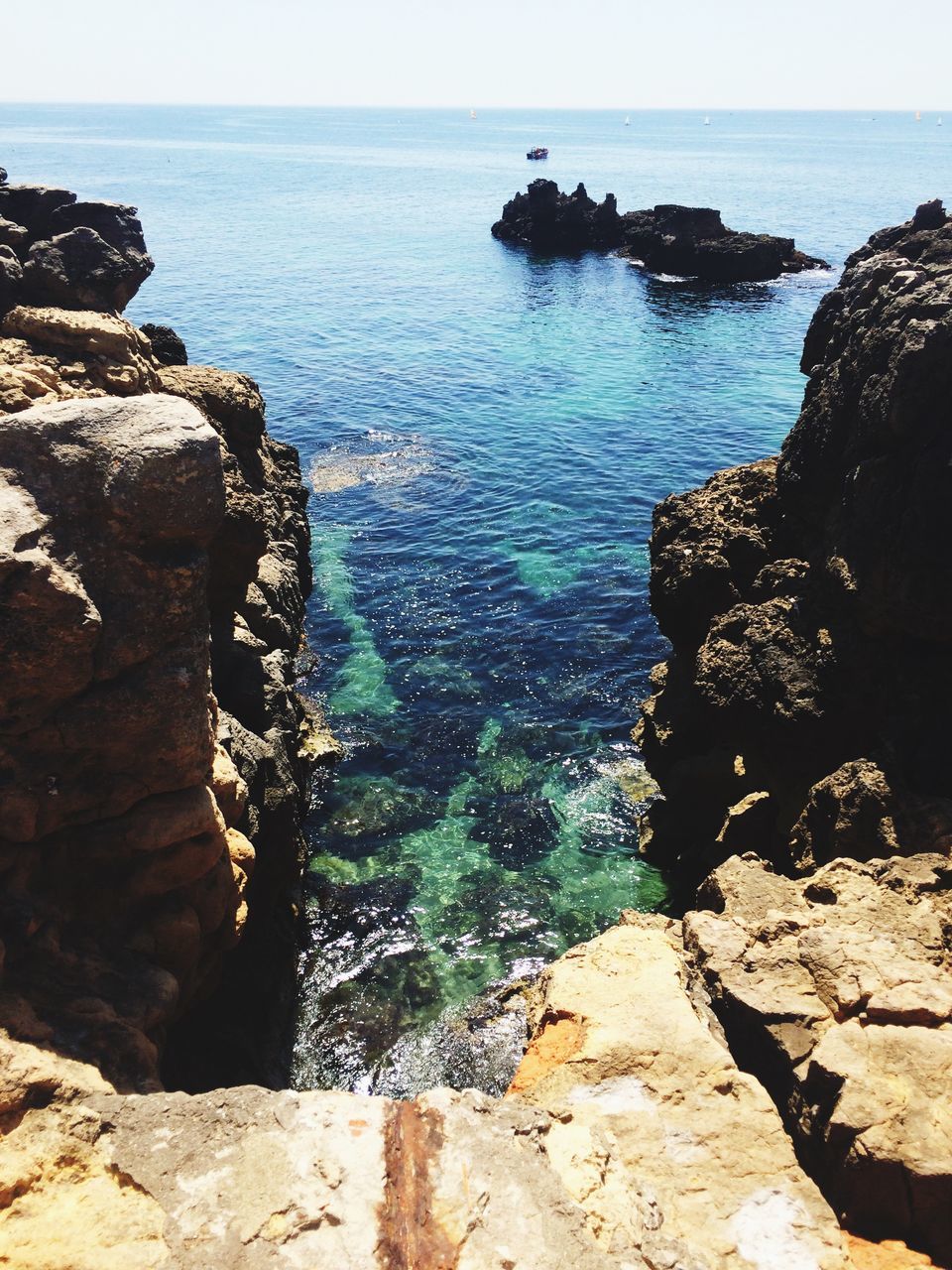 sea, water, horizon over water, rock - object, rock formation, tranquil scene, tranquility, scenics, beauty in nature, rock, cliff, nature, high angle view, idyllic, blue, shore, sunlight, coastline, outdoors, sky