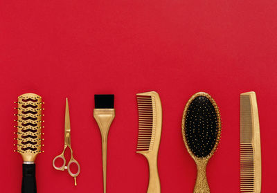 Background with hairdressing tools on red. hair salon accessories gold, hair combs, scissors. 