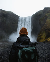 Rear view of person looking at mountain against sky