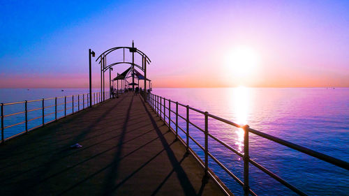 Pier over sea against sky during sunset