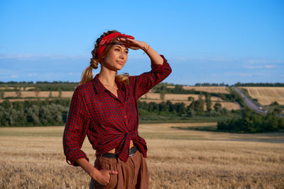 Woman looking away while standing on land against sky