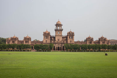 View of historical islamia university of peshawar against clear sky and green carpeted grass. 