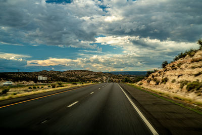 Road leading towards mountains against sky