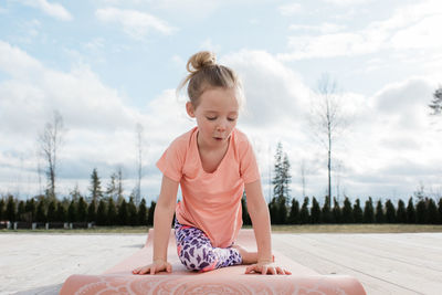 Young girl doing yoga stretching in her back yard at home