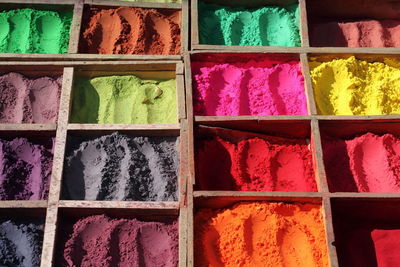 Full frame shot of colorful powder paints in wooden containers at market stall