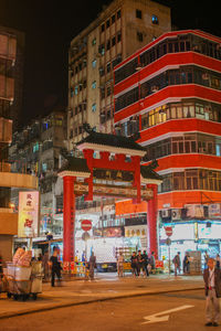 People on street amidst buildings in city at night