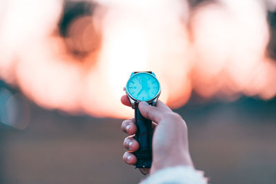 Cropped hand of woman holding wristwatch