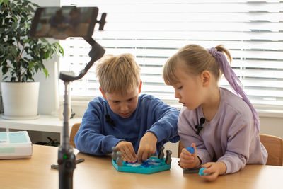 Siblings playing with toy blocks at home