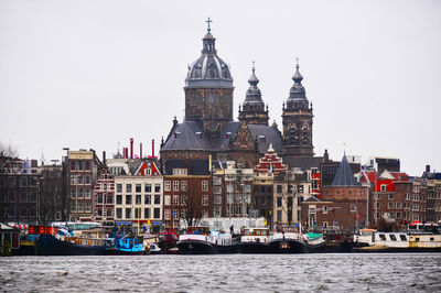 Boats in canal amidst buildings against clear sky