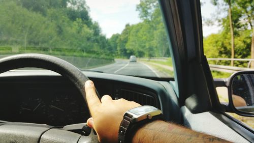 Hand on steering wheel of car