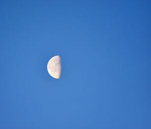 Low angle view of moon against clear blue sky