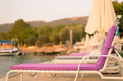 Lounge chairs on pier by sea