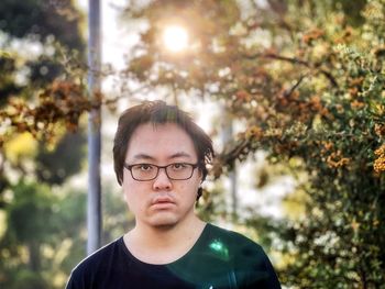 Portrait of young asian man standing against orange rowan berry trees.