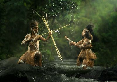 Asmat people catching fish on the river by an arrow