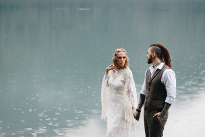 A loving married couple the bride and groom in suits celebrate wedding near the mountains and water