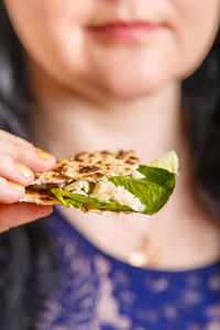 A woman without a face holds matzo and maror in her hand. vertical photo