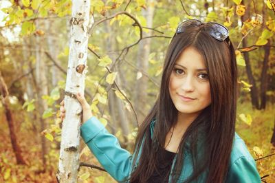 Portrait of woman standing on tree trunk