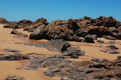 Rock formations at beach against clear sky