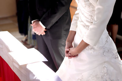 Midsection of bride holding wedding dress