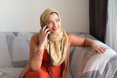 Smiling young woman using mobile phone at home