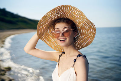 Portrait of young woman wearing hat standing at beach