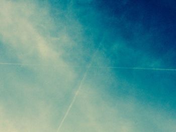 Low angle view of vapor trails against blue sky