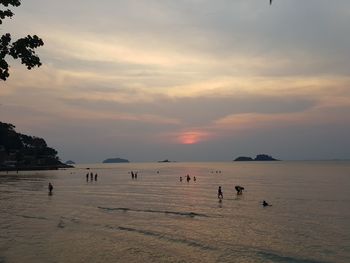 People on beach against sky during sunset