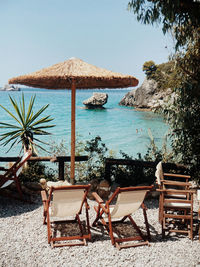 Deck chairs on beach against clear sky