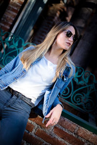Portrait of young woman sitting on brick wall