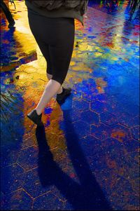 Low section of woman standing on multi colored umbrella