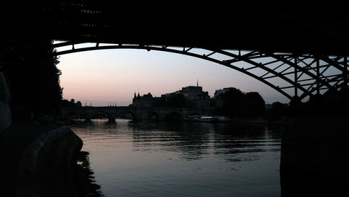 Silhouette of bridge over river during sunset