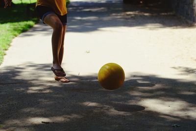 Low section of woman playing with ball on street