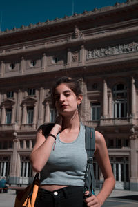 Portrait of beautiful woman standing against building in city