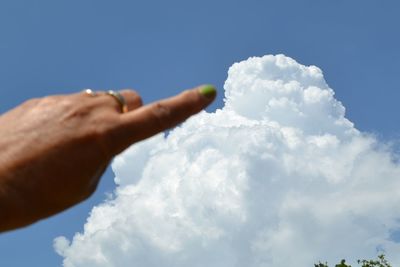 Optical illusion of hand touching clouds